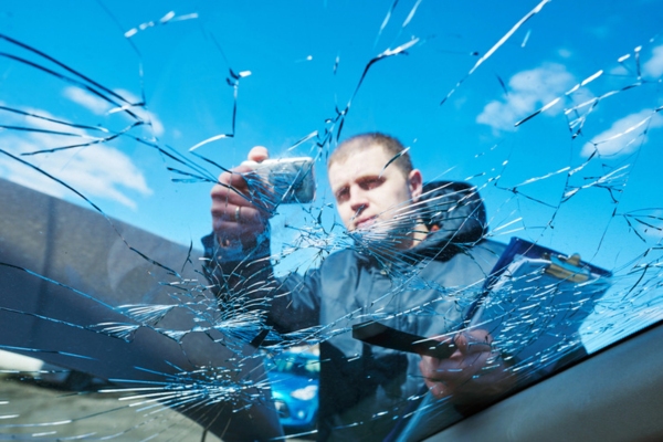 worker holding a folder taking a picture of a broken windshield