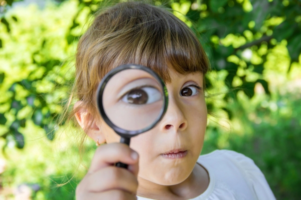child looking through a magnifying glass depicting Closer Look at the History and Technology of Auto Glass