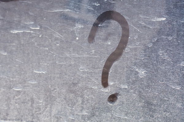 question mark on a dirty glass surface depicting FAQs about Driving With a Nonfunctional Side Window