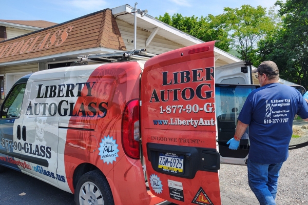 Liberty AutoGlass worker loading a windshield in a service van