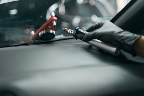 gloved hand on a windscreen holding a drill for a windshield