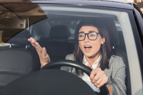 woman speaking while driving depicting Why Windshield Leaks Occur