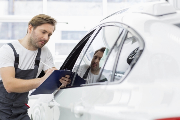 professional auto glass repairman writing on a clipboard after evaluating a car
