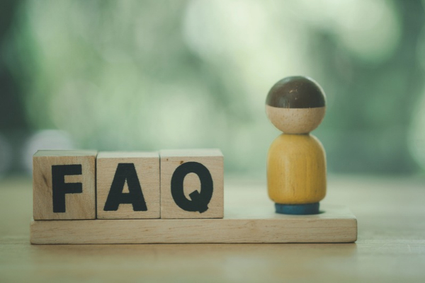 FAQ spelled using wooden letter cubes beside a wooden carved miniature figure depicting Windshield Replacement Tips questions