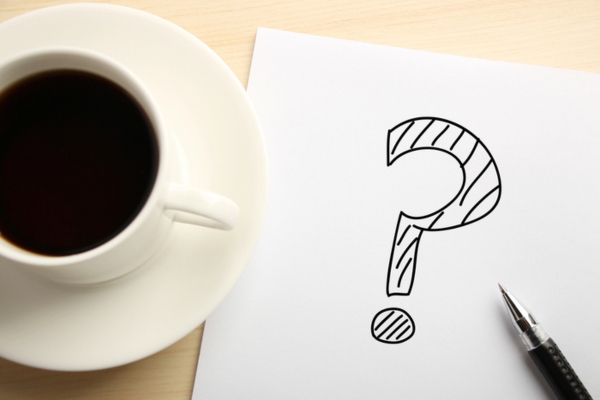 question mark doodled on paper beside coffee cup depicting Rock Hit Windshield FAQs