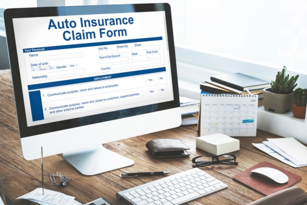 computer on a working desk with auto insurance claim form displayed on screen