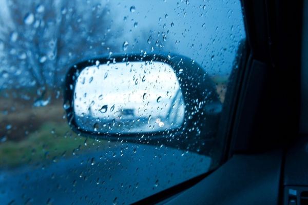 car view on side mirror with water drops from rain