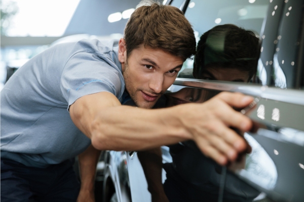 man inspecting car auto glass to prepare for summer road trip