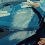 woman wiping car windshield depicting lifespan of windshield