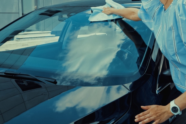 woman wiping car windshield depicting lifespan of windshield