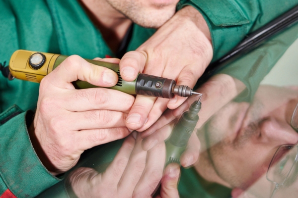 worker using precision tool on a car windscreen