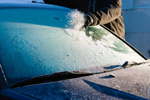 cropped view of a man removing ice on frozen windshield