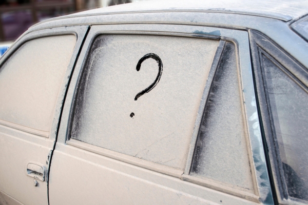 unwashed car with a question mark doodled on the side window depicting Road Salt Damage to Windshield FAQs