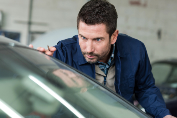 mechanic inspecting windshield of a vehicle